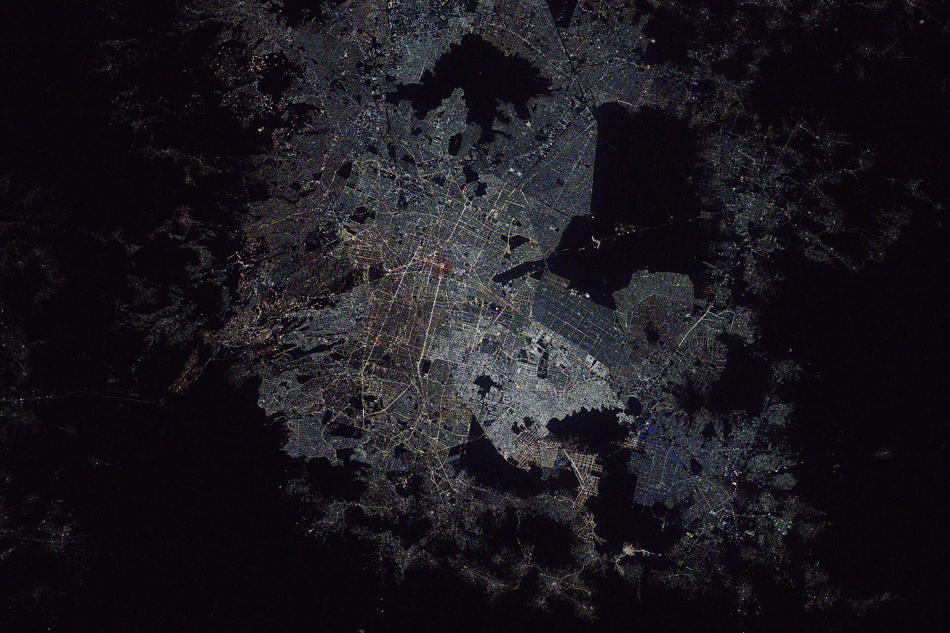 Mexico City's lights filling the valley between dark mountains at night