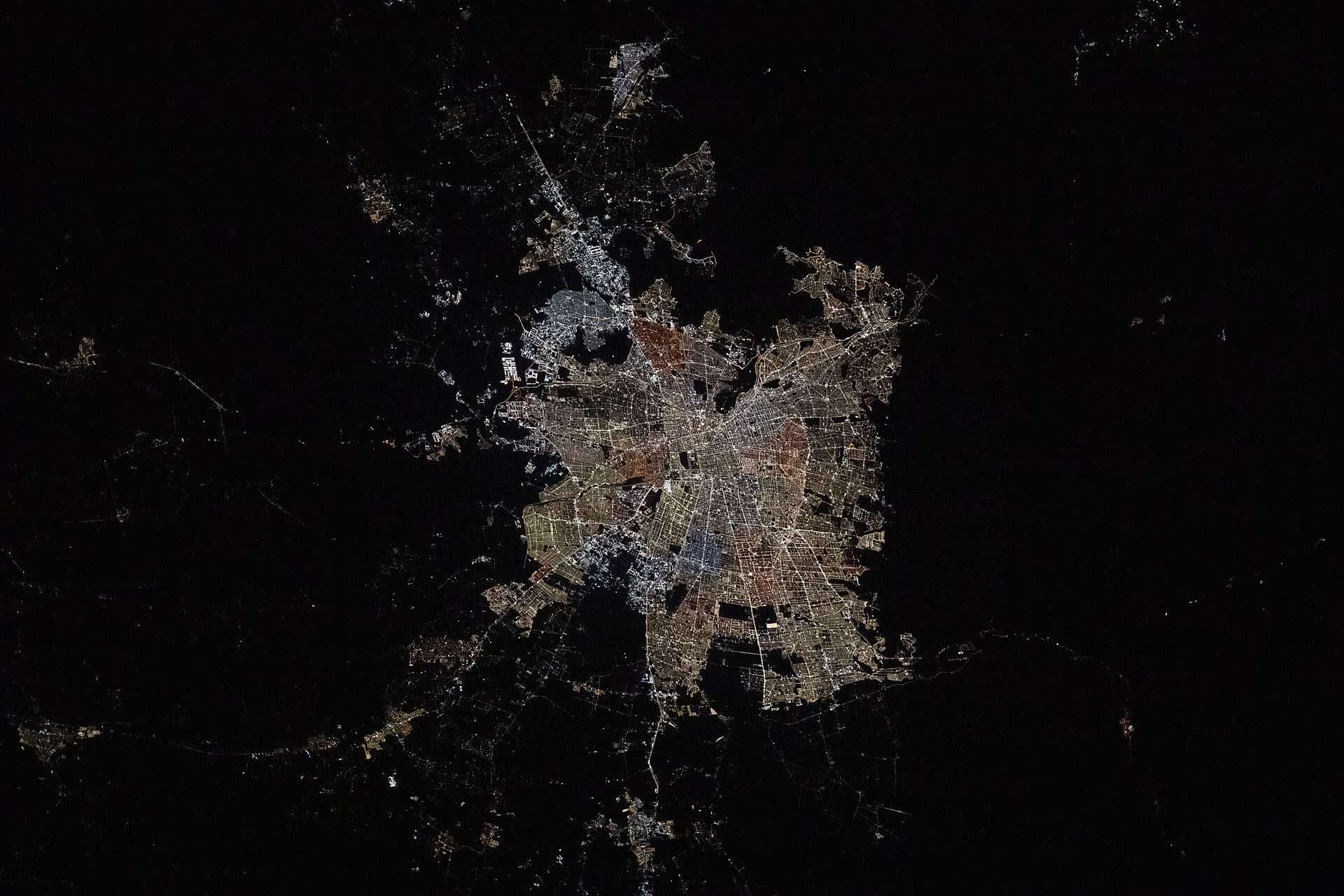 Santiago de Chile's lights in a dark valley below the Andes at night